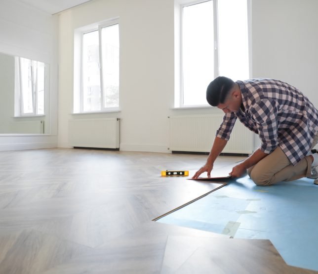 Professional worker installing new parquet flooring indoors